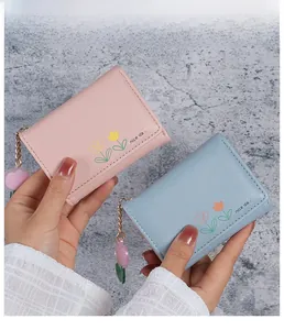 Gros plan de mini portefeuilles tricolores rose et bleu avec motif floral et chaîne