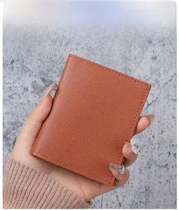 Close-up of caramel leather card holder with litchi texture held in hand