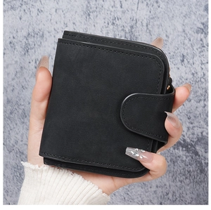 Close-up of black matte short wallet with button strap and fine stitching detail