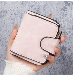 Close-up of a pink small bifold wallet with matte suede finish and gold zipper detail