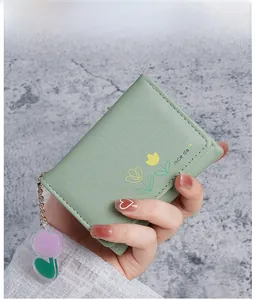 Gros plan sur un portefeuille vert clair avec motif tulipe et breloque mignonne