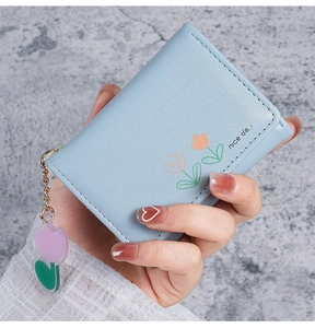 Gros plan d'un petit portefeuille bleu clair avec motif floral et pendentif coeur
