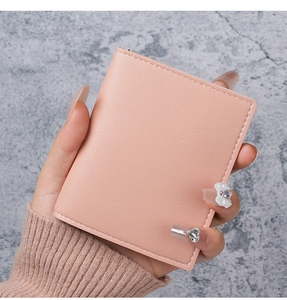 Detail of pink faux leather card holder with white stitching held by hand