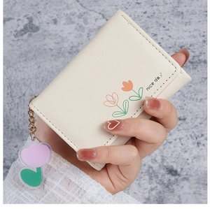 Détail du portefeuille en cuir PU blanc crème avec motif tulipe et charm acrylique
