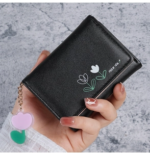 Gros plan du portefeuille noir avec imprimé floral, texte et porte-clé fleur assorti