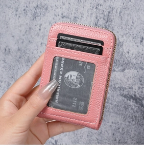Pink pebbled leather card holder featuring 12 slots and zipper closure held by hand
