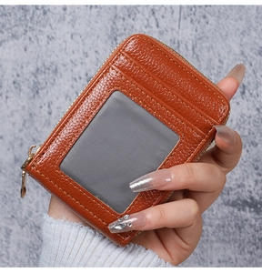 Close-up of caramel brown pebble leather card holder with clear ID window and zipper closure