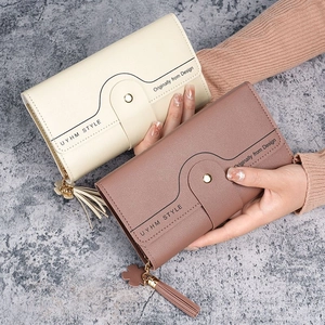 Minimalist long trifold leather wallet for women with tassel and floral charm in hand