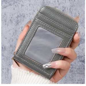 Close-up of grey litchi grain leather card holder with zip closure and transparent ID window