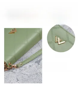 Dettaglio del portafoglio verde trapuntato con logo dorato e cinturino da polso