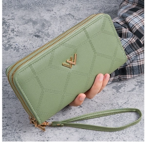 Dettaglio del portafoglio lungo verde chiaro con doppia zip e trama trapuntata geometrica