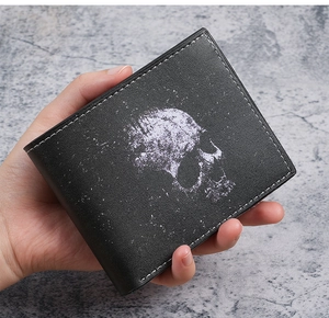 Detailed view of skull print on black leather short wallet with contrast white stitching