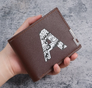 Close-up of brown bifold leather wallet with decorative letter A and floral print