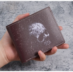 Close-up of vintage skull print wallet with white stitching held in hand