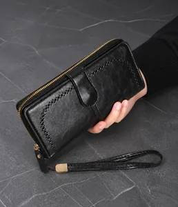 Detail of black long leather wallet with hollow punch pattern and gold metal zipper