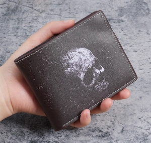 Close-up of vintage skull print on brown bifold wallet with contrast white stitching