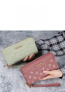 Detailed view of long zip wallets with quilted floral embroidery and wrist strap