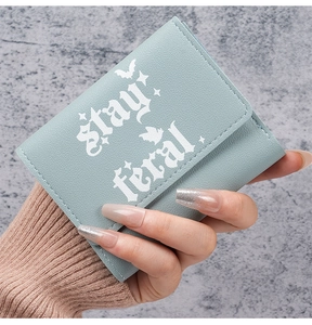 Close-up of light blue trifold wallet featuring gothic Stay Feral lettering and bats