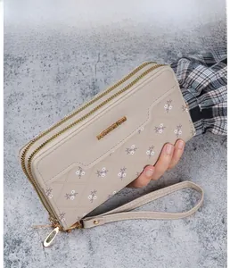 Detail of long beige quilted wallet with floral print, dual zippers and wrist strap