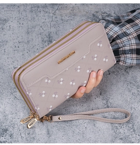 Detail of lavender long wallet with floral embossing, dual zippers, and wrist strap