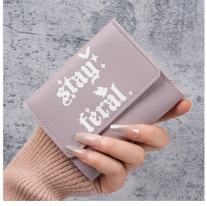 Close-up of lavender leather wallet featuring stay feral gothic text and bat details