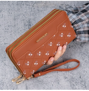 Detail of caramel quilted wallet with floral embroidery and dual metal zippers