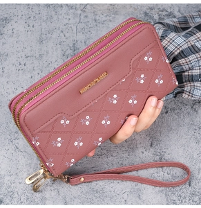 Detail of dual zipper long wallet with floral print, quilted pattern and wrist strap