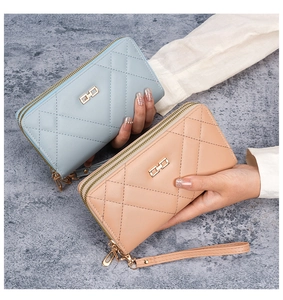 Close-up of light blue and pink quilted leather wallets with double zippers and wrist straps