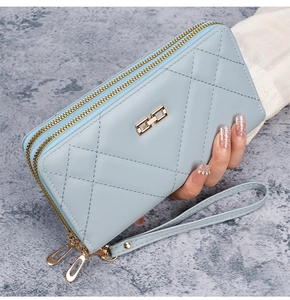 Detail of light blue quilted leather long wallet with dual zippers and gold hardware