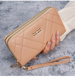 Detail of light beige quilted wallet with double zippers and gold H-shaped buckle metal accent