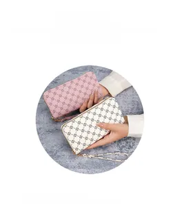Detail of pink and beige long wallet featuring vintage clover pattern and gold zipper