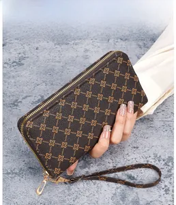 Detail view of long brown zip wallet featuring gold floral patterns and matching wrist strap
