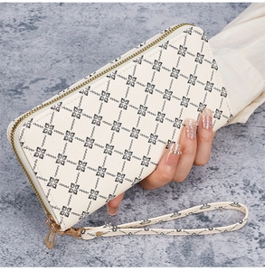 Detailed view of cream-colored long zipper wallet with black floral pattern and wrist strap