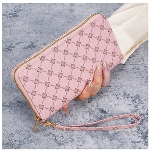 Detail of pink long leather clutch wallet with clover pattern and gold zipper