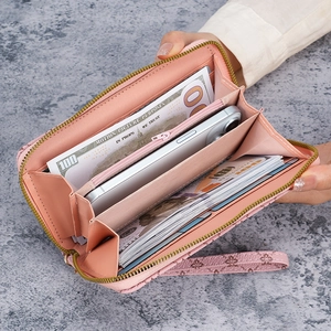 Pink embossed floral long wallet with zipper and wristlet strap on marble background