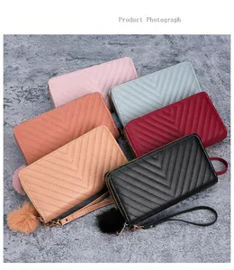 Detail view of colorful V-quilted long wallets with pompom charms and wrist straps