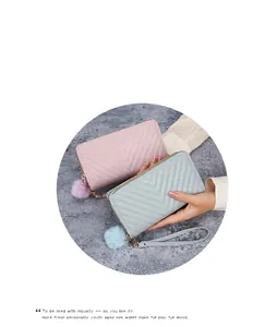 Detail view of V-quilted long wallets in pink and blue with plush ball charms and straps