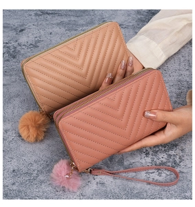 Close-up of quilted V-pattern long wallets in beige and pink with pompom charms