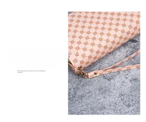 Detail of light pink floral clutch bag with detachable wrist strap and gold metal hardware