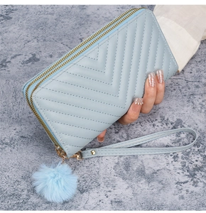 Detail of light blue chevron quilted wallet with double zippers and plush ball charm