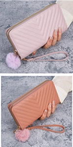 Close-up of dual zipper long wallet with V-quilted pattern and plush ball charm in pink