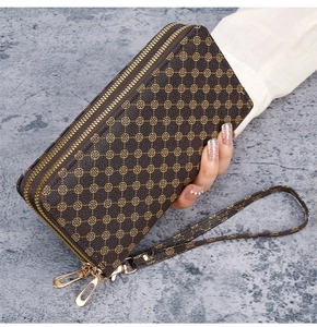 Detail of a brown floral print double zipper clutch bag with a detachable wrist strap