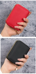Close-up of red and black lychee textured leather card wallets with gold zipper detail