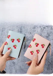 Close-up of pink and blue short wallets with cherry embroidery and metal zippers