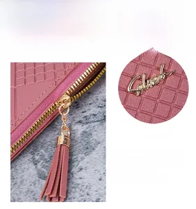 Détail du portefeuille rose avec texture gaufrée et fermeture éclair dorée à gland