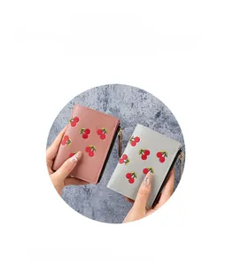 Close-up of cherry embroidery details on pink and blue leather mini wallets
