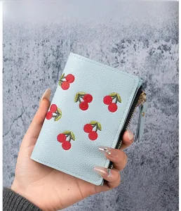 Close-up of light blue cherry embroidery on pebbled faux leather wallet with zipper