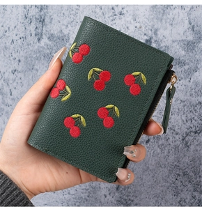 Detail of green litchi leather wallet with red cherry embroidery and side zip pocket