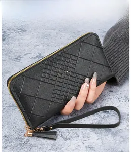 Gros plan d'un portefeuille long en cuir noir matelassé avec pompon et zip doré