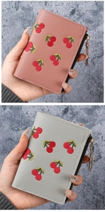Detail of compact short wallet with cherry embroidery and golden zipper texture